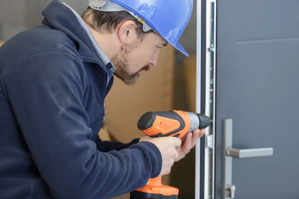 Artisan préparant la pose d'une serrure sur une porte de garage