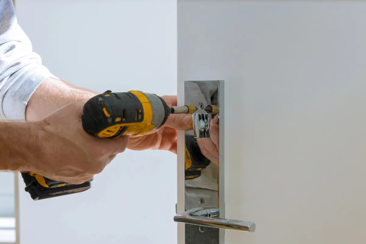 Fixation d'une garniture de serrure chromée sur une porte blanche